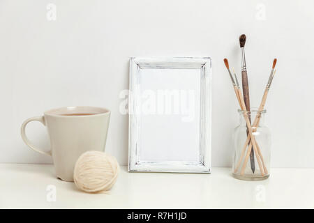 Maquette du châssis vertical avec une tasse à café près de mur blanc. Cadre vide maquette pour sa présentation. L'ossature pour modèle l'art moderne Hygge Scandinavie Banque D'Images