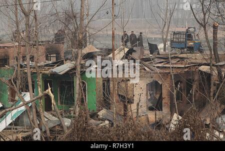 Les gens passent devant les maisons endommagées dans Mujgund dans la banlieue de Srinagar, au Cachemire sur Décembre 09, 2018. Quatorze ans, a été parmi les trois militants tués en 18 heures-épaule bataille sur la périphérie de Srinagar. L'Inde n'éclatent les affrontements anti massive dans de nombreuses parties du Cachemire dès que la nouvelle du meurtre de la propagation des militants, la police a utilisé des gaz lacrymogènes, des grenades assourdissantes et des granulés à disperser les manifestants en colère. Plus de cinq maisons ont été endommagés par les forces indiennes où les militants auraient été tués. (Photo par Faisal Khan/Pacific Press) Banque D'Images