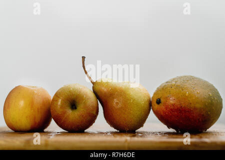 La pomme, poire et mangue dans une rangée avec goutte d'eau, copy space Banque D'Images
