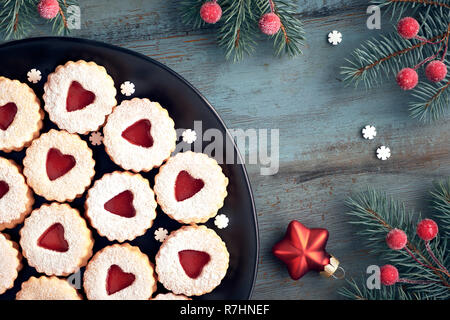 Vue de dessus de linzer cookies de Noël traditionnel avec de la confiture rouge sur fond de bois rustique décoré de petits fruits, srars et flocons.Ce sont des tradi Banque D'Images