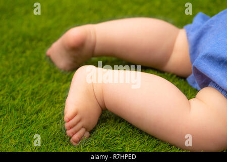 Pieds d'un petit bébé sur le vert gazon artificiel Banque D'Images