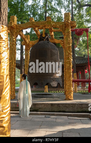 Les femmes en robe bouddhiste traditionnel debout devant de grosse cloche de bronze dans la région de Little White Goose Pagoda park, Xian, Chine Banque D'Images