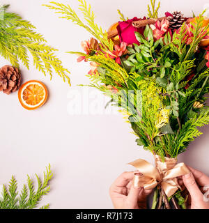Fleuriste femelle fait un Noël hiver bouquet de conifères et de fleurs. Banque D'Images