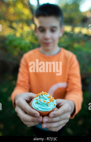 Boy holding blue color muffin. Close up Banque D'Images