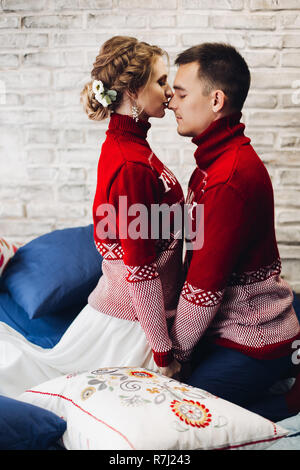 Couple kissing cavaliers de Noël entouré d'oreillers. Banque D'Images