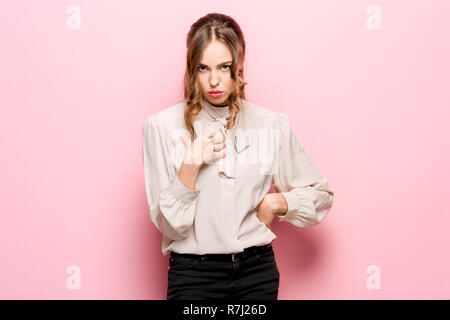 Une femme demande qui je suis, montrant sur eux-mêmes les doigts. Belle femelle portrait en pied isolé sur fond rose studio. Les jeunes surpris émotionnelle woman looking at camera.les émotions humaines, l'expression faciale concept Banque D'Images