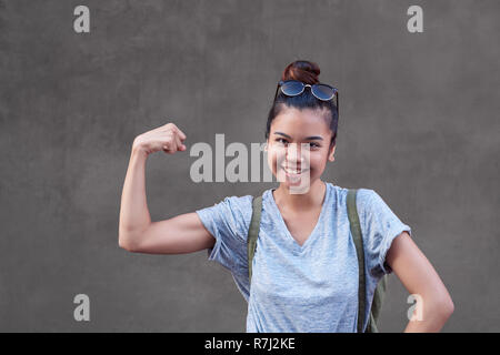 Femme Asiatique joyeux sourire lors de la torsion ses biceps à l'extérieur Banque D'Images