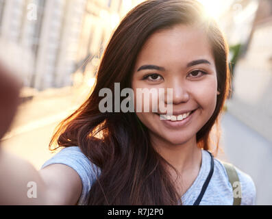 Content Young Asian woman marcher dans la ville en tenant vos autoportraits Banque D'Images