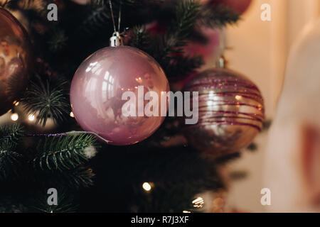 Arbre de Noël avec des arcs et des rubans à carreaux roses et humeur de fête près de cheminée. Banque D'Images