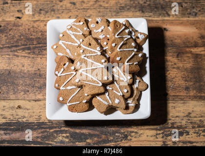 Plaque carrée blanche avec diverses formes de biscuits de pain d'épices sur fond de bois, la composition du paysage Banque D'Images