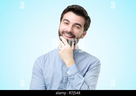 Handsome man en shirt looking at camera debout sur fond bleu lumineux Banque D'Images