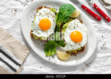 Vue de dessus les toasts avocat sain pour le petit déjeuner ou le déjeuner avec le pain de seigle, pain grillé et purée d'avocat d'œufs au plat sur fond blanc Banque D'Images