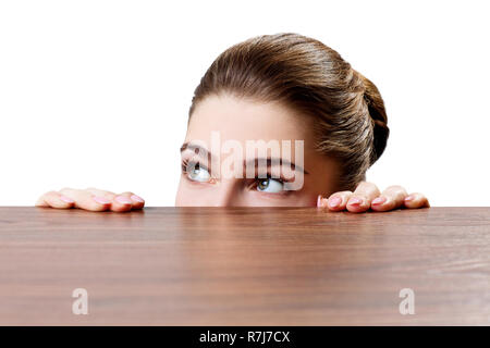 Femme peeping sous le bord de table en bois sur fond blanc. Banque D'Images