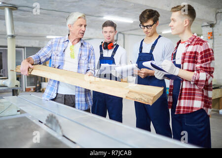 Carpenter montrant planche en bois aux stagiaires Banque D'Images