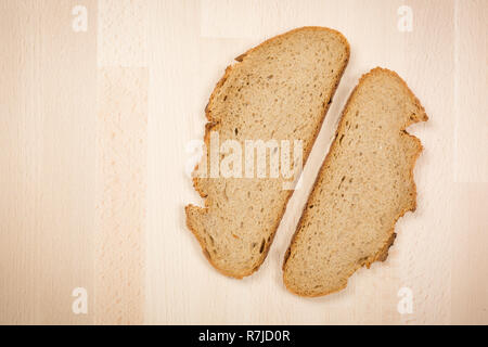 Deux tranches d'un pain typiquement allemand allongé sur une table en bois hêtre. Coup de gros plan ci-dessus. Ce pain est composé de 50 % de seigle. Il a une croûte croustillante. Banque D'Images