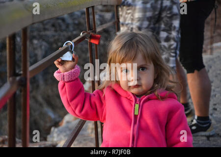 Peu curieux girl kid holding le cadenas sur le garde-fou Banque D'Images