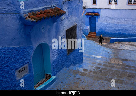 Le Maroc, Chefchaouen, Medina, enfant en bas de l'étroite rue de maisons à flanc de colline peinte en bleu Banque D'Images