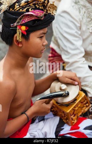 Denpasar, Bali, Indonésie - Juin 23, 2018 : l'homme musicien en costume de danse traditionnelle à l'airain gong ( partie de l'orchestre gamelan balinais ) Banque D'Images