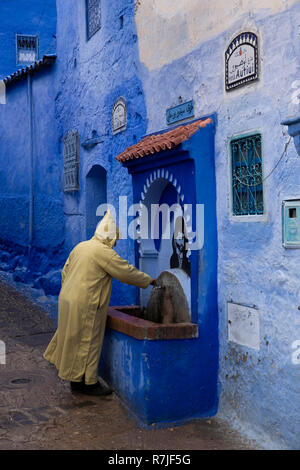 Mc457, Chefchaouen, Maroc, Medina, l'homme Autiui Avenida en djellaba à fontaine d'eau traditionnelle Banque D'Images