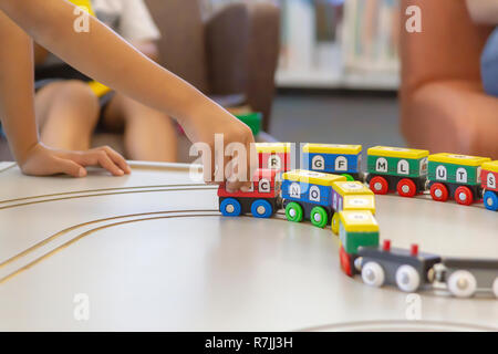 Une main​ l'enfant tire le train le long. Le train coloré avec des lettres de l'alphabet et les chiffres tout autour sont magnétiquement peint connecté. Banque D'Images