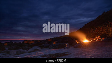 Feu de camp sur la plage, avec le coucher du soleil. Longue exposition. Banque D'Images