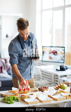 Waist up portrait of smiling photographe prendre des photos d'aliments avec table de travail Banque D'Images