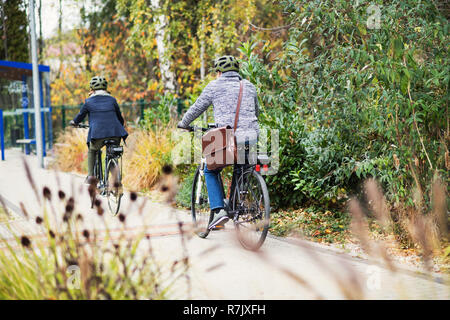 Une vue arrière du couple actif avec electrobikes vélo en plein air sur sentier en ville. Banque D'Images