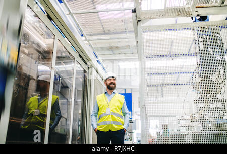 Un portrait de l'homme industriel ingénieur dans une usine, les mains dans les poches. Banque D'Images