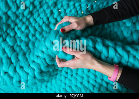 Girl holding une couverture de laine mérinos couverture tricotée, close-up. Banque D'Images