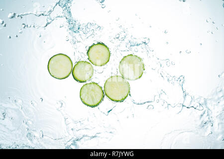 Les courgettes les éclaboussures d'eau sur fond blanc Banque D'Images