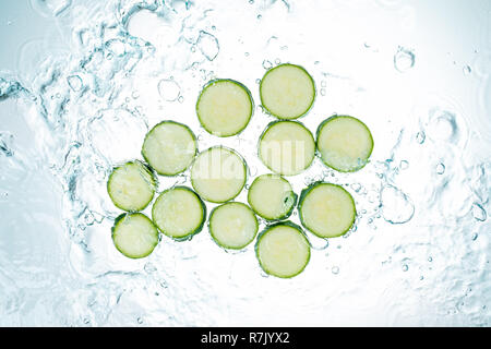 Les courgettes les éclaboussures d'eau sur fond blanc Banque D'Images