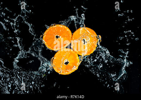 Les oranges, les éclaboussures d'eau sur fond noir Banque D'Images
