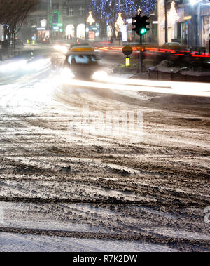 Rue de la ville floues couverte de neige avec des traces de pneus et de conduire des voitures light trails in winter Night Banque D'Images