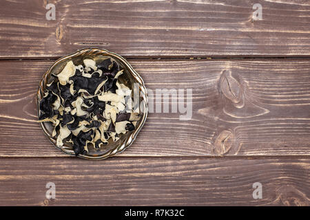 Beaucoup de tranches de champignons noirs secs oreille juif dans divers vieux bol de fer flatlay sur bois marron foncé Banque D'Images