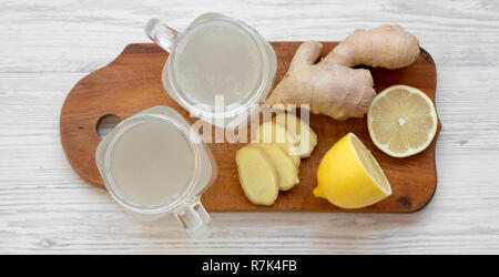 Thé au citron gingembre maison dans des bocaux en verre sur planche de bois sur la surface en bois blanc, vue de dessus. Mise à plat, d'en haut, vue d'en haut. Banque D'Images