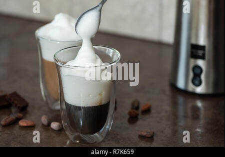 Mousse de lait est mis dans un verre de café. Banque D'Images