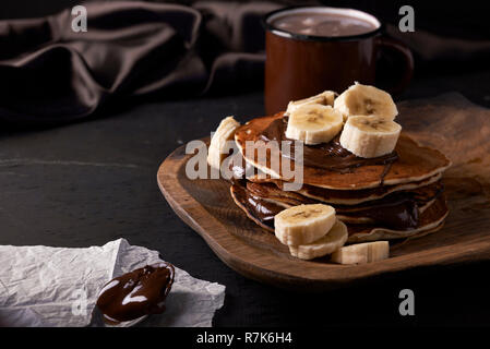 Des crêpes et de la banane et chocolat propagation sur plaque de bois Banque D'Images