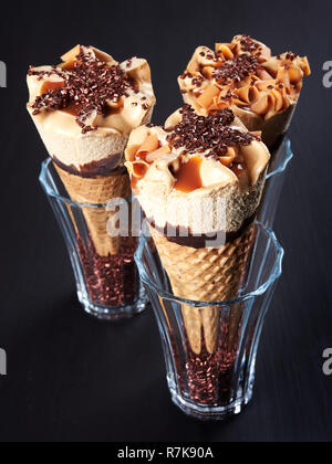 Trois cornets de crème glacée au caramel, mettre dans des verres remplis de cristaux de sucre, sur fond marron foncé Banque D'Images