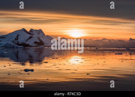 Coucher de soleil sur le lagon des icebergs à la dérive de l'Antarctique avec la neige et les pics dans l'arrière-plan, le Canal Lemaire, l'Antarctique Banque D'Images