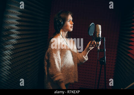 Jeune femme séduisante grave chanter dans un studio d'enregistrement Banque D'Images