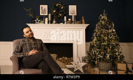Beau jeune homme barbu hippie dans roomthinking de Noël des idées de cadeaux. La rêverie. Banque D'Images