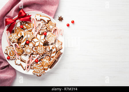 Plaque avec gingerbread cookies de Noël décoré avec des arc rouge sur le tableau blanc. Vue de dessus, copiez l'espace. Banque D'Images