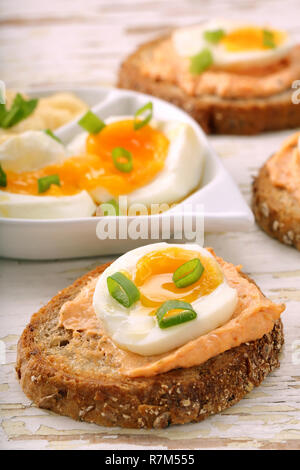 Sandwiches avec de la pâte de saumon et oeuf sur le fond en bois blanc Banque D'Images