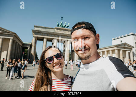 Belle jeune couple contre selfies l'arrière-plan de la porte de Brandebourg à Berlin en Allemagne. Banque D'Images