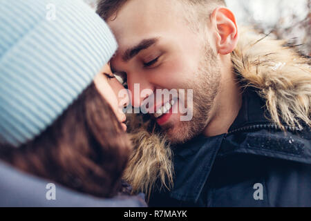 Beau aimer couple hugging in winter forest. Les gens de toucher le nez et sourit. Close up Banque D'Images