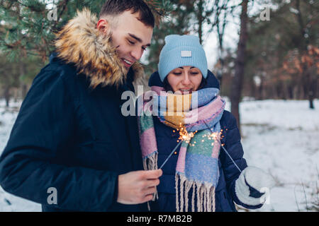 Beau couple aimant cierges brûlant dans la forêt d'hiver. Noël et Nouvel an fête concept Banque D'Images