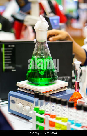 Agitateur de laboratoire magnétique. Le liquide vert est mélangé dans un flacon en verre conique. Banque D'Images