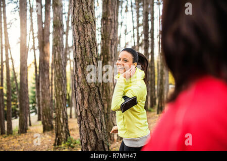 Dames avec écouteurs et le jogging à l'extérieur de la forêt dans les smartphones. Banque D'Images