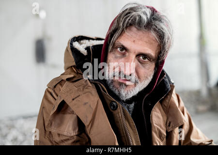 Portrait d'un sans-abri mendiant homme assis à l'extérieur. Banque D'Images