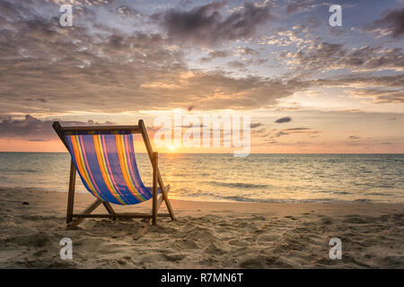 Une chaise vide à la plage isolée pendant le coucher du soleil Banque D'Images